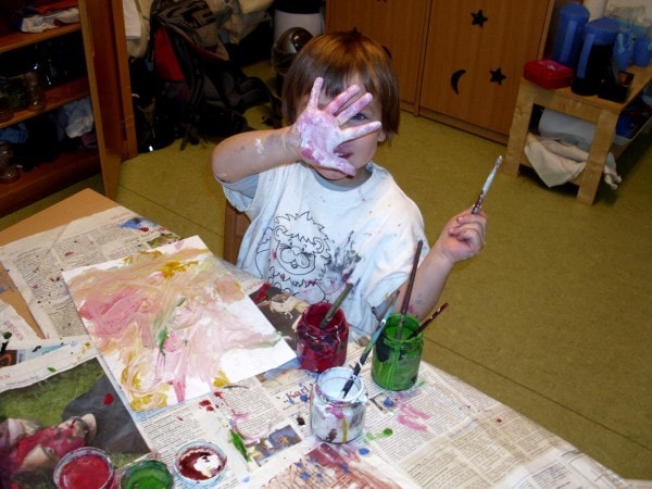 Kindergartenkind malt mit Farbe und verteilt die Farbe mit der Hand