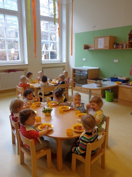 Krippenkinder an runden Tischen beim Essen